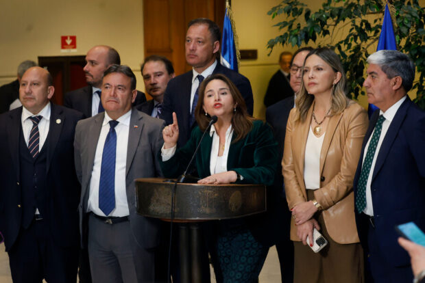 La diputada, Joanna Pérez, en punto de prensa tras votación de sufragio obligatorio. En la imagen la parlamentaria está entregando declaraciones desde un podio rodeada de otros legisladores.