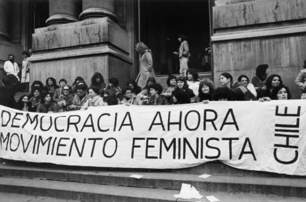 Un grupo de mujer extiende una pancarta que dice: "Democracia ahora. Movimiento feminista. Chile".