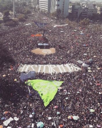 Vista área de una multitud de mujeres reunidas en una marcha. Entre las personas se ve escrito en el suelo "HISTÓRICAS".