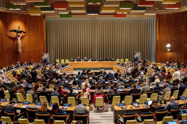 Una vista panorámica de una sala de conferencias con múltiples delegados y representantes reunidos. 
