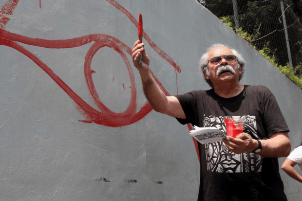 El muralista Mono González pintando los primeros trazos de un mural.