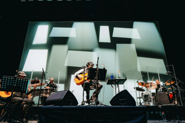 Silvio Rodríguez tocando guitarra sobre el escenario del Movistar Arena en Chile.
