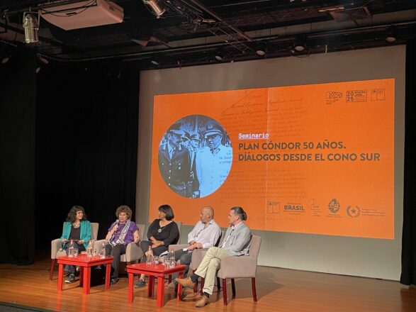 Panel de cuatro oradores (tres mujeres y un hombre) sentados en un escenario frente a una pantalla proyectando el título "Plan Cóndor 50 Años. Diálogos desde el Cono Sur", en un seminario o conmemoración.
