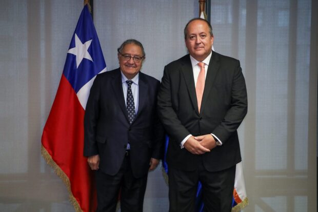 Senadora Francisco Huenchumilla (DC) y el fiscal nacional, Ángel Valencia., posan sonrientes para una foto, de pie al lado de la bandera de Chile
