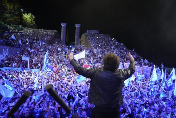 Javier Milei se ve de espaldas frente a una gran multitud que celebra en un espacio abierto.