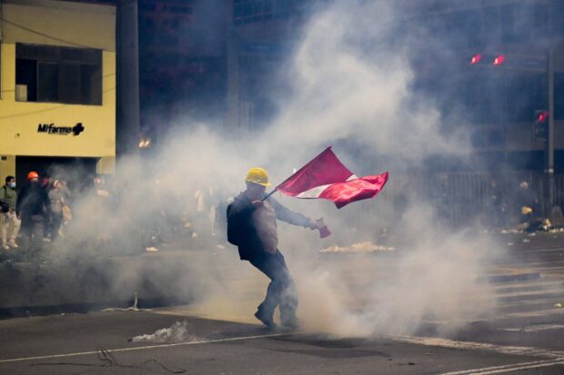 Manifestante portando la bandera peruana en medio de las protestas en Lima. Vía X@MiguelVsquezVi1