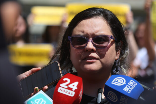 Priscila González, integrante de la coordinación nacional de la Red Chilena Contra la Violencia., rodeada de micrófonos de distintos medios de comunicación.