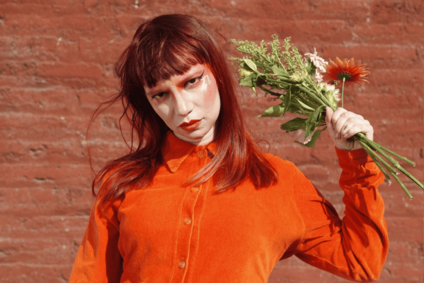 Chini.png, artista chilena, sosteniendo un ramo de flores.