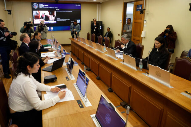 Mesa de trabajo en la sala de la Cámara de Diputados, con congresistas de izquierda y derecha sentados frente a computadores.