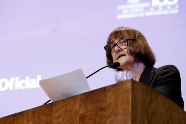 Rectora de la Universidad de Chile, Rosa Devés, habla desde un podio de madera sosteniendo una hoja blanca en sus manos.