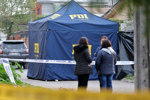 Carpa azul de la PDI (Policía de Investigaciones de Chile) en un sitio de suceso, con cinta de peligro y personas observando.