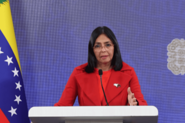 Vicepresidenta de Venezuela, Delcy Rodríguez, habla desde un podio. A su derecha la bandera de Venezuela.