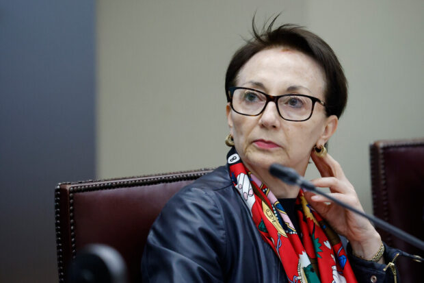 Gloria Ana Chevesich, ministra de la Corte Suprema, sentada en una sesión institucional, usando lentes y pañuelo, frente a un micrófono.