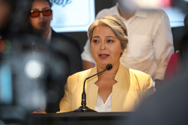 Punto de prensa de Jeannette Jara. Vestida de traje amarillo y blusa blanca hablas desde un podio con micrófono.