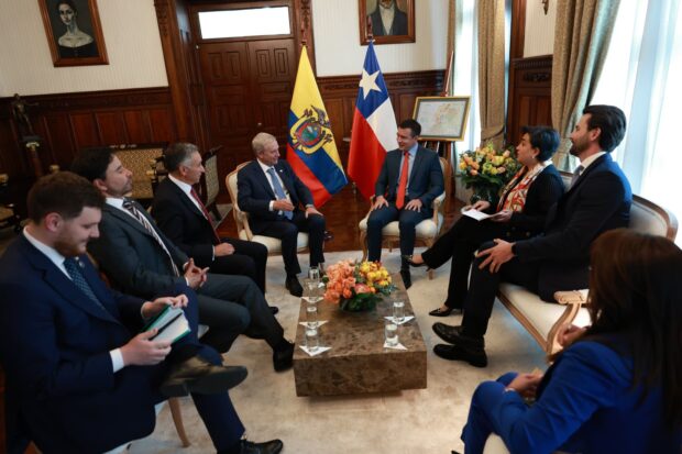 José Antonio Kast y Daniel Noboa sentados en una oficina formal con las banderas de Ecuador y Chile al fondo, rodeados por sus equipos de trabajo en una mesa de diálogo.