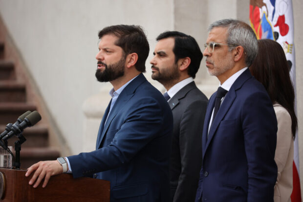 Presidente Gabriel Boric habla desde un podio, detrás de él dos ministros y una ministra de Estado.