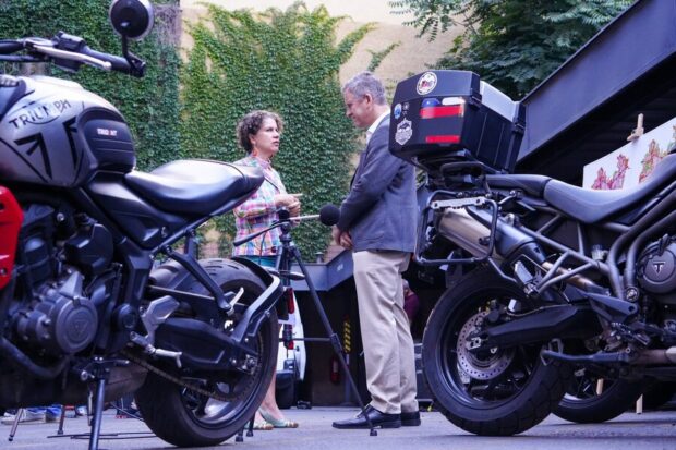 Los ministros Juan Carlos Muñoz y Maisa Rojas conversan entre motos estacionadas.