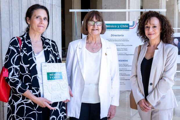 Tres mujeres posan en un espacio institucional durante la presentación del libro “México-Chile. Una historia de asociación estratégica”; una de ellas sostiene el ejemplar.