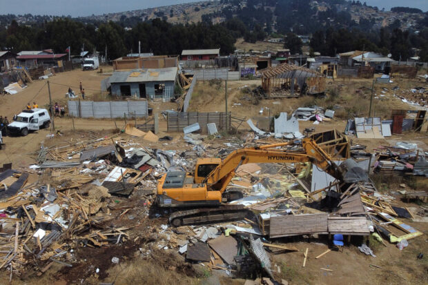 Maquina retroexcavadora amarilla destruye viviendas de la megatoma de San Antonio