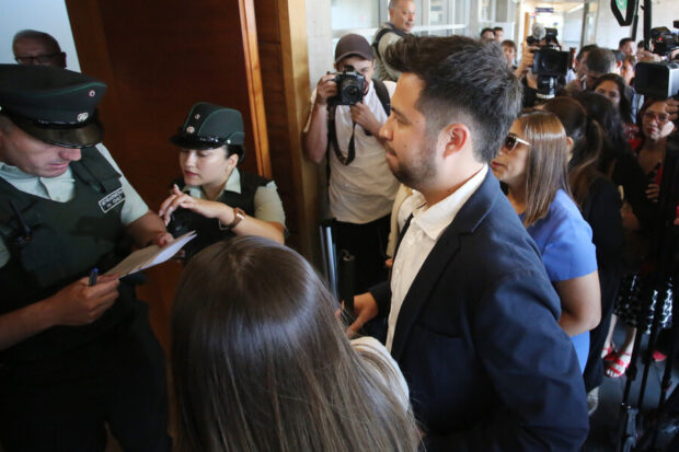 Diputado electo Gustavo Gatica rodeados de varias personas mientras entra al tribunal de justicia.