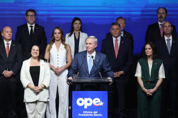 Kast habla desde un podio con un grupo de personas ordenadas atrás de él.