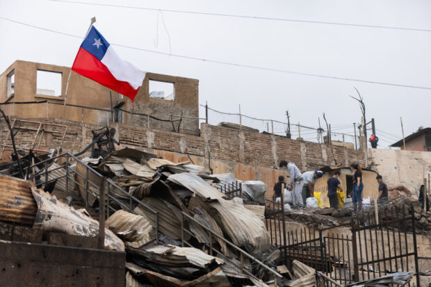 Personas levantan escombros de las viviendas destruidas por los incendios forestales.