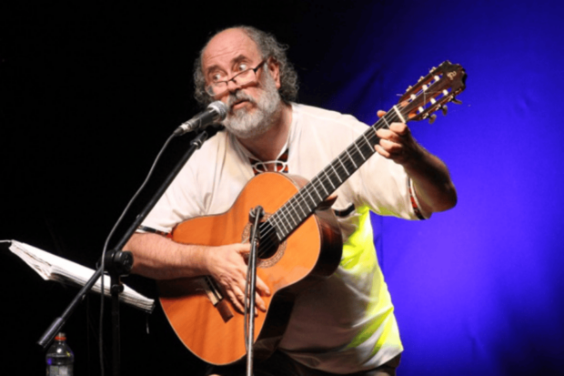El músico Eduardo Peralta tocando guitarra sobre el escenario.