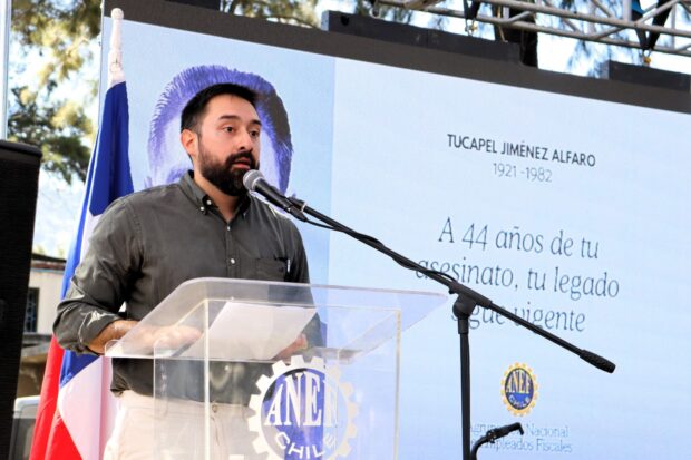 Sebastián Jiménez, nieto de Tucapel Jiménez, habla desde un podio transparente con el logo de la ANEF.
