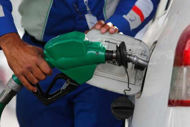 Trabajador de Copec echando bencina en un auto blanco.