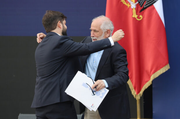 Boric y Montes a punto de abrazarse, detrás de ellos se una parte de la bandera de Chile.