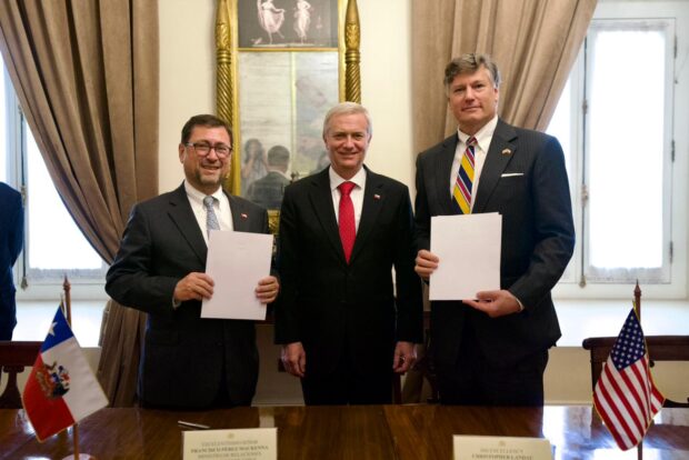 Presidente de la República, José Antonio Kast, junto al vicesecretario de Estado estadounidense, Christopher Landau, y el canciller Francisco Pérez Mackenna, posan a la cámara sosteniendo unos documentos.