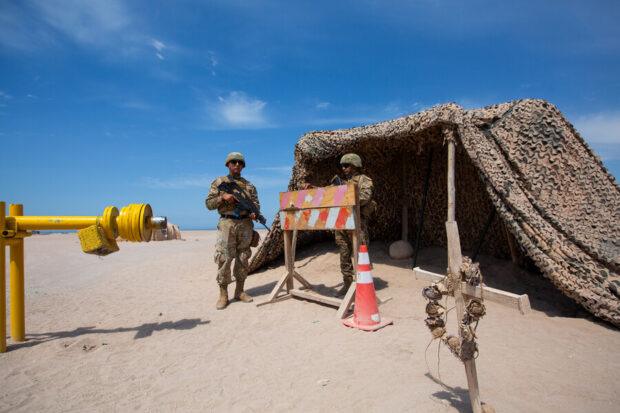 Militares en el desierto, atrás de ellos una carpa militar.