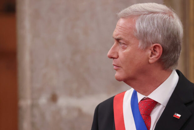 Presidente José Antonio Kast fotografiado de perfil, vertido de traje negro, corbata roja y la banda presidencial tricolor.