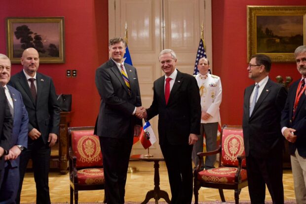 Presidente de la República, José Antonio Kast, y el vicesecretario de Estado estadounidense, Christopher Landau, posan sonriendo y con un apretón de manos.