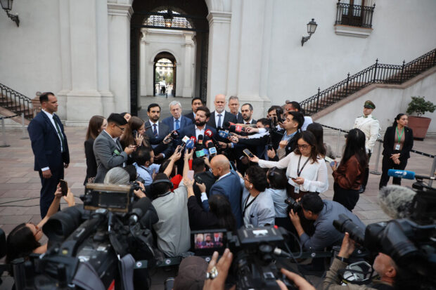 Presidente Gabriel Boric rodeados de micrófonos de medios de comunicación en un punto de prensa. En la imagen, se ve a Boric frente a una decena de periodistas, camarógrafos y con autoridades de Estado detrás.