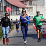 Personas trotando y andando en patines al aire libre en una calle cerrada para el deporte.