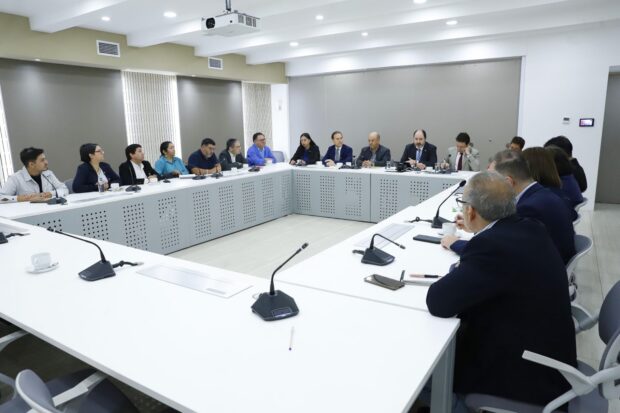 Representantes de la CUT y el Ministerio del Trabajo reunidos en una sala de conferencias. Dirigentes y autoridades están sentados en una mesa en forma de U.