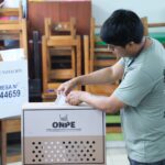 Hombre deposita su voto en una urna de cartón con el logo "ONPE Oficina Nacional de Procesos Electorales".