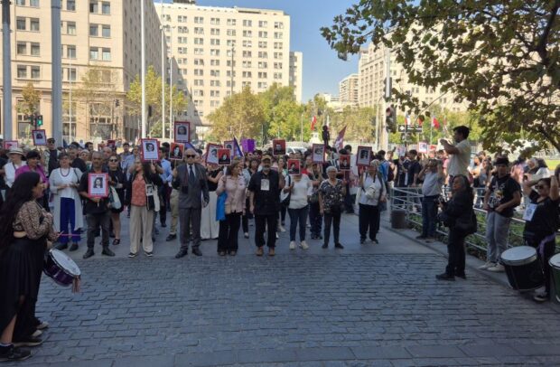 Un grupo de personas se manifiesta y sostiene fotografías de sus familiares desaparecidos por la dictadura civil-militar.