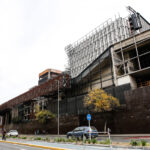 Vista aérea de las obras de ampliación del Centro Cultural Gabriela Mistral (GAM) en Santiago. Se observa la estructura metálica y de hormigón rodeada de andamios frente a la Alameda, con la Torre Telefónica de fondo.