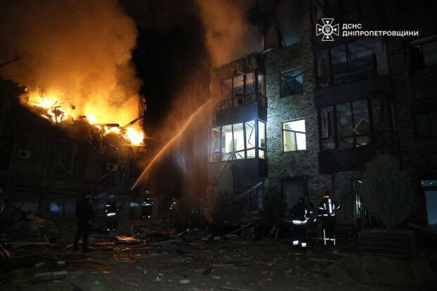 Bomberos combaten un incendio masivo en un edificio residencial. Se observan daños estructurales significativos y el suelo cubierto de escombros.