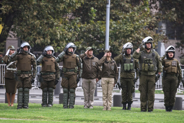 Carabineros formados realizando un saludo militar a la bandera.