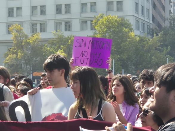 Personas se manifiestan con pancartas y lienzos. Una sostiene un cartel con la frase "Sin memoria no hay futuro". 