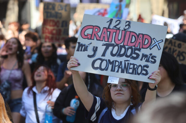 Manifestantes en una marcha. En primer plano se ve una pancarta que dice: "1, 2, 3, gratuidad para mi y todos mis compañeros".