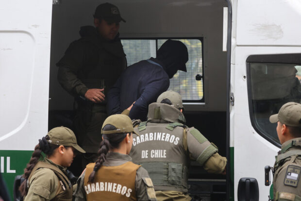 Efectivos de Carabineros de Chile trasladan a un detenido hacia el interior de un furgón policial.