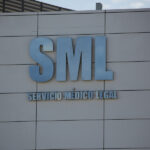 Letrero metálico azul con las siglas "SML" y el texto "Servicio Médico Legal" sobre la fachada gris de un edificio institucional.