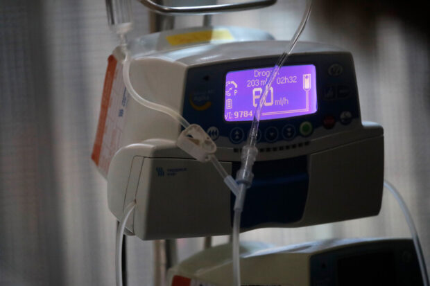 Un equipo médico de infusión intravenosa con pantalla digital encendida, conectado a tubos y bolsas de suero.