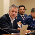 Exministro de Transportes, Juan Carlos Muñoz, sentado frente a un micrófono durante una sesión de comisión en el Congreso.