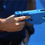 Mano sujetando una pistola taser azul.