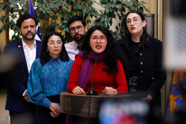 Diputada Serrano habla desde un podio acompañada de 4 diputados que están detrás de ella.